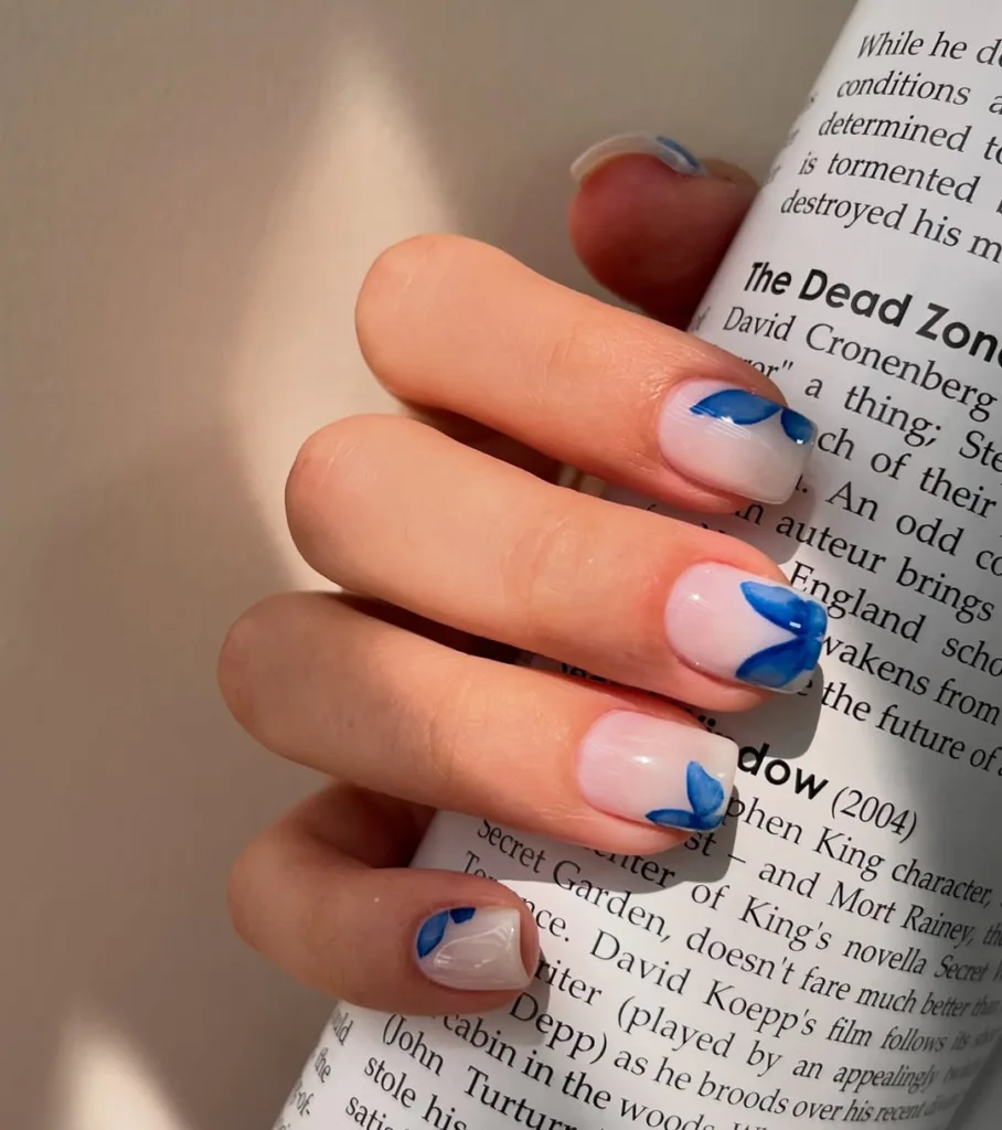 Transparente Nägel mit zarten blauen Schmetterlingsspitzen für eine verträumte Frühlingsstimmung.
