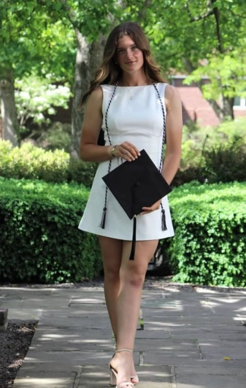 Ein ärmelloses weißes Kleid mit schwarzen Quastenakzenten, ideal für Abschlusszeremonien, die einen formellen und stilvollen Look ausstrahlen.