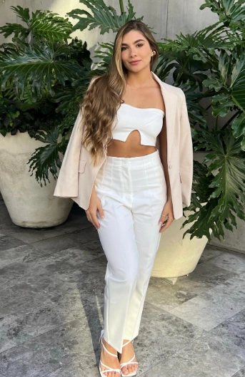 Ein stilvolles Abschluss-Outfit mit einer weißen, geschnittenen Oberseite, hoch taillierten weißen Hosen und einem leichten beige Blazer, perfekt für formelle Anlässe.