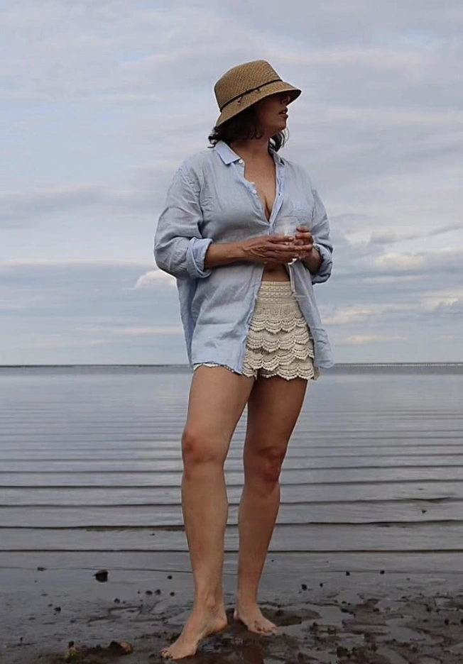 Ein lässiges Outfit mit Spitzenshorts in Beige, gepaart mit einem hellblauen Button-up-Hemd, perfekt für Strandausflüge.