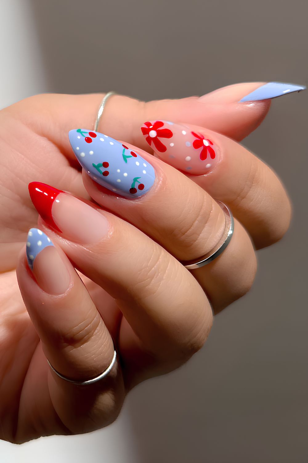 Blaue und rote Nägel mit Kirschen und Blumen
