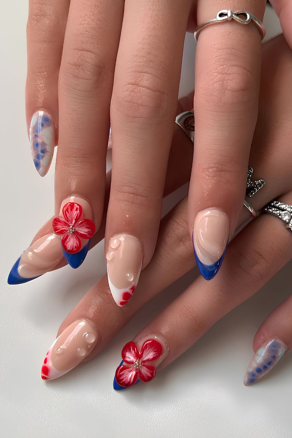 Rote und blaue Nägel mit 3D -Blumen