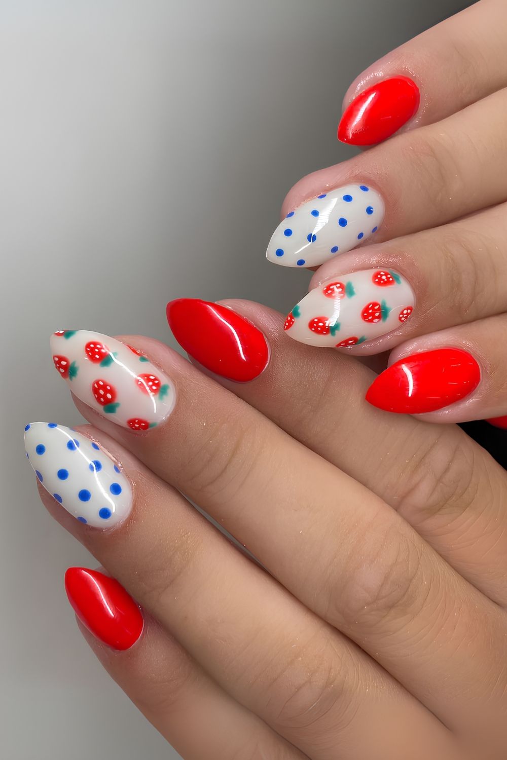 Rote Nägel mit blauen Punkten und Obstkunst